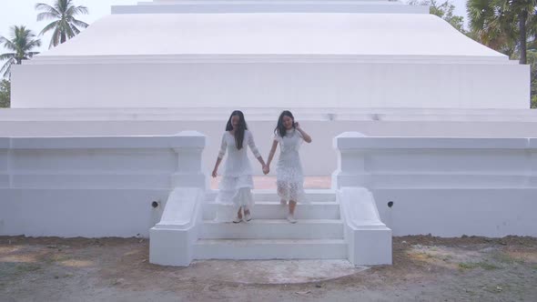 Two Asian Girls Holding Hand And Having Fun On Summer Travel Near The Temple alt