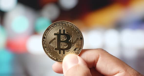 Holding bitcoin with the city bokeh view at night alt