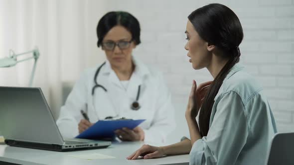 Female Doctor Keeping Medical Records, Young Woman Patient Saying Symptoms alt