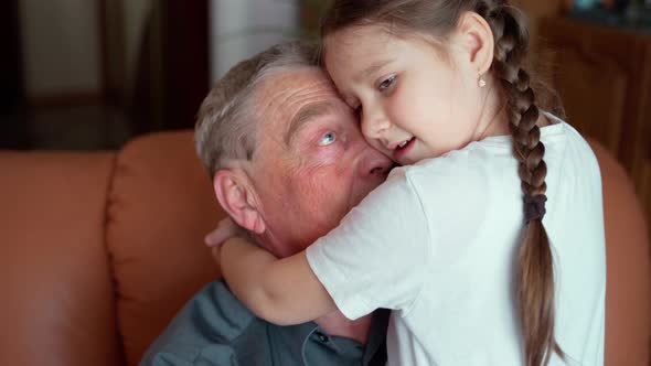 Smiling loving young little granddaughter hug old elder grandfather at retirement home