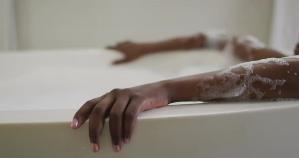African american attractive woman relaxing in foam bath in bathroom alt