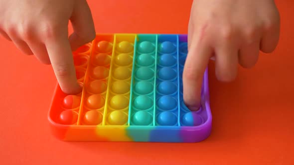 Child playing with rainbow pop it,top view.New antistress toy for children and adult alt