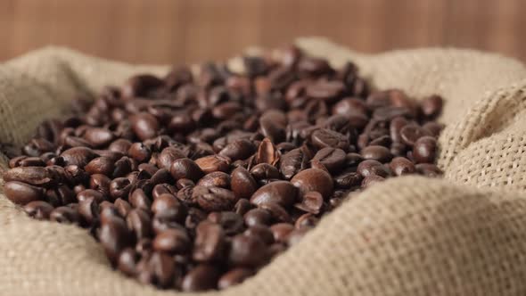 From Above Dark Coffee Beans Fall Into an Ecobag Made of Burlap