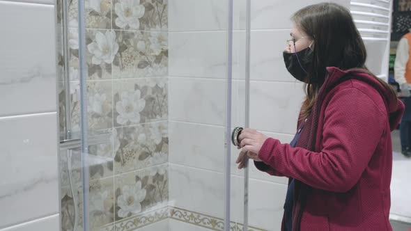 Woman Wearing an Against Virus Mask Stands in Store and Chooses New Shower Stall