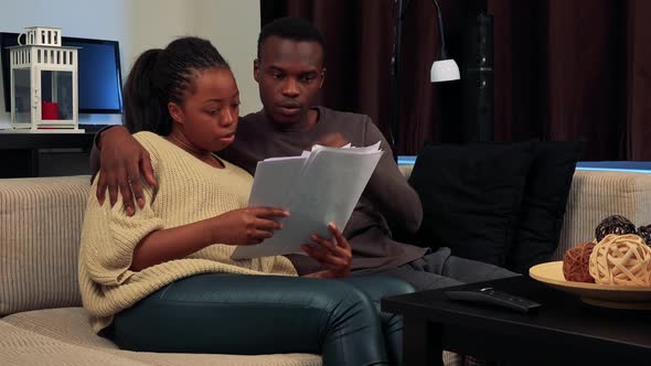 Young Black Couple Read Some Documents and Talk About It in Living Room  alt