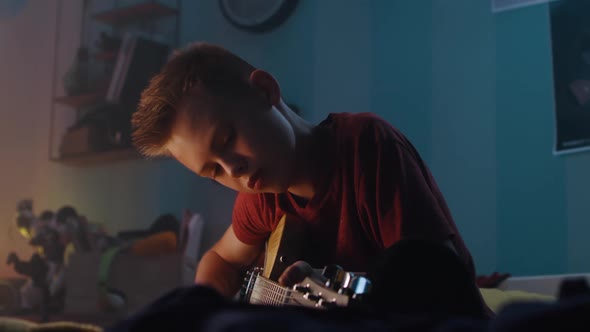 Teenager Playing Guitar in Evening alt