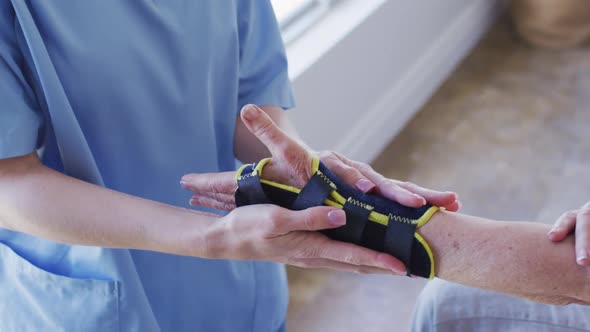 Mid section of female health worker putting face mask on senior woman at home alt