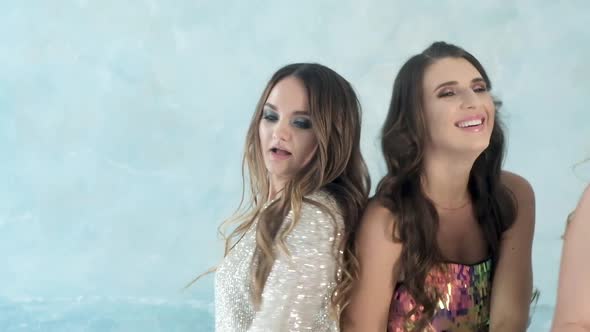 party with girlfriend. Girls in shiny evening dresses actively dance and laugh. alt