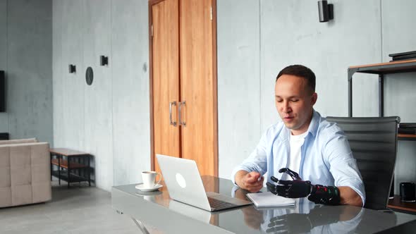 Cheerful guy company manager with black bio hand prothesis talks at online video alt