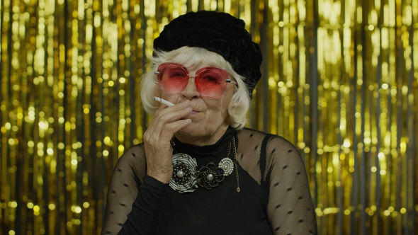 Elderly Style Mature Grandmother in Fashion Black Clothes in Sunglasses Posing, Smoke Cigarette alt