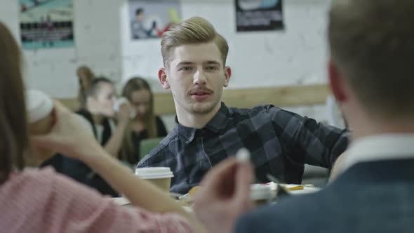 Young Professional Using Gadget and Chatting with Coworkers alt