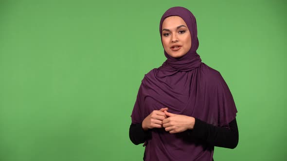 A Young Beautiful Muslim Woman Talks to the Camera with a Smile  Green Screen Background