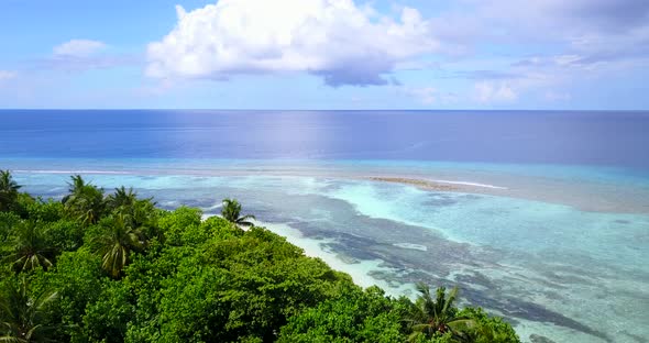 Wide above island view of a sandy white paradise beach and turquoise sea background in 4K alt