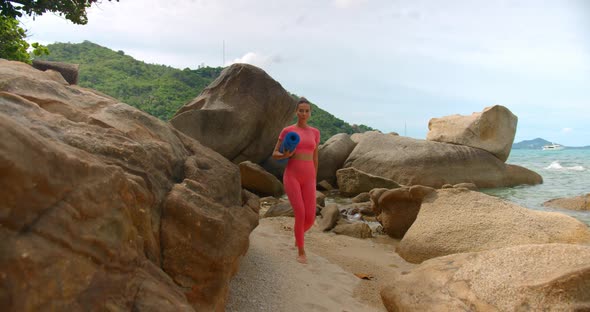 Millennial Woman Walking on the Beach for Morning Exercise She Walks Between the Rocks to the Spot alt