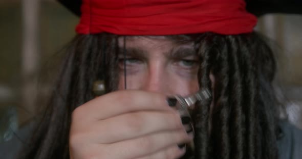 Portrait of Pirate in Cocked Hat and Wig with Dreadlocks Decorated with Beads Who Takes Out Small