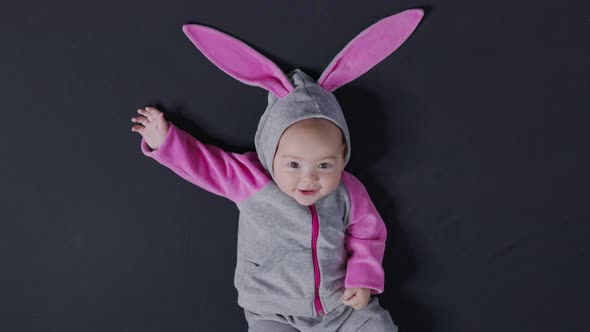 Cute Baby Smiling and Looking in the Camera Close Up. Little Kid in Easter Bunny Costume, Top View. alt
