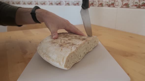 Close-up on hands cutting traditional bolo do caco bread of Madeira. Handheld shot alt