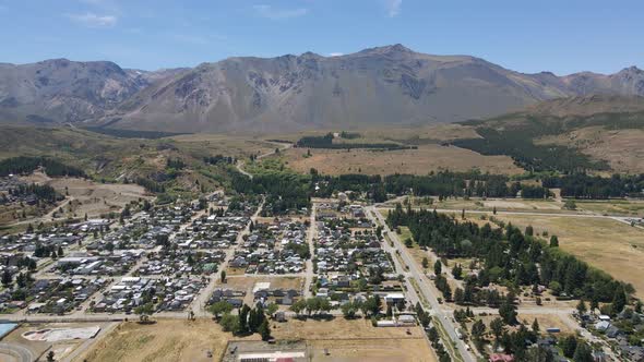 Dolly in flying over Esquel city surrounded by woods with mountains in background, Patagonia Argenti alt