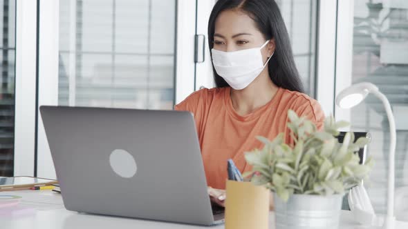 Attractive businesswoman using laptop working in the office wearing a mask.