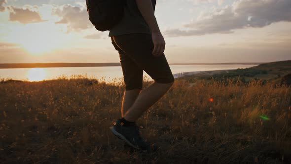 Male Photographer with Backpack and Tripod in It is Walking Along Meadow on Plato of a Mountain and alt