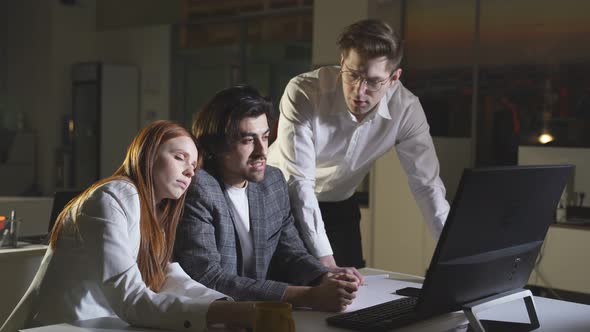 A Team of Young People Works Hard Late at the Office at the Computer Works Overtime alt