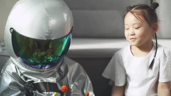 Asian Kids Play in the Living Room at Home a Boy in an Astronaut Costume Sitting on the Floor with