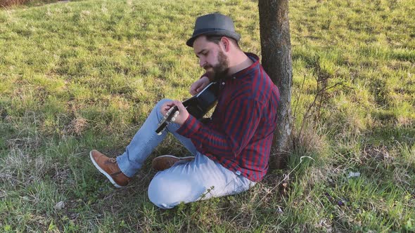 Slow motion shot of man playing acoustic guitar outdoors