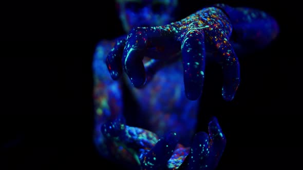 Young Man Painted with Fluorescent Paints Makes Movements with Hands As Holding an Energy Ball Front alt