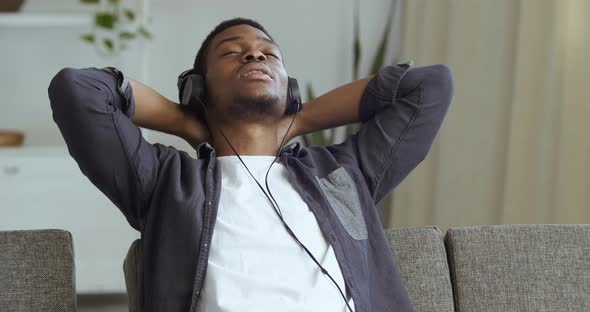 Portrait of Calm Young African Businessman Ethnic Student Wear Wireless Headphone Relax with Eyes alt