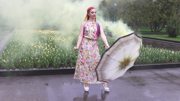 Girl with African Braids and Makeup in Spring Dress is Dancing in the Rain with Umbrella in Yellow alt