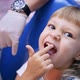Little child in stomatology chair points at the ill tooth with a finger - close up video. - VideoHive Item for Sale
