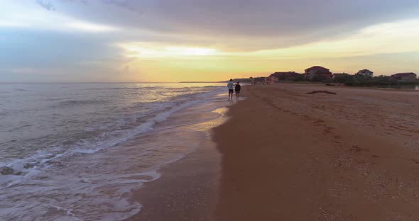 Man and woman walk along the beach in the evening at sunset.