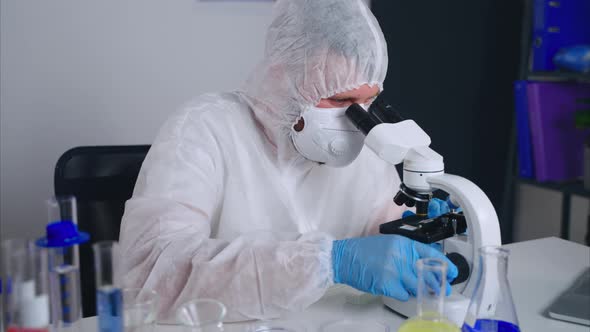 Microbiologist is Viewing New Virus or Bacteria in Microscope Working in Laboratory alt