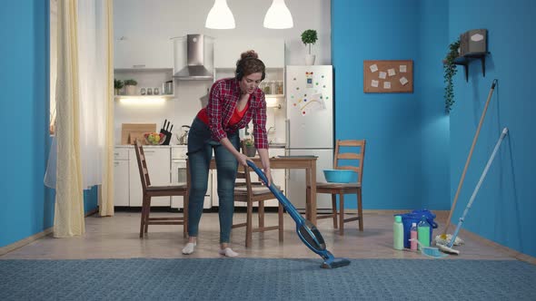 Housewife Cleans the Carpet with a Vacuum Cleaner. alt