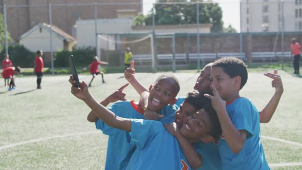 Soccer kids in blue taking a selfie and laughing in a sunny day alt