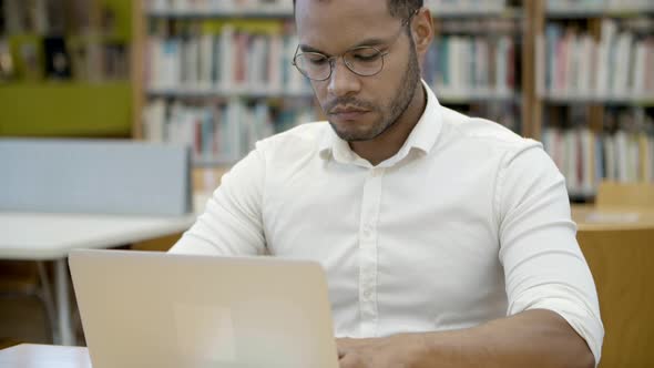 Concentrated Student in Eyeglasses Typing on Laptop alt