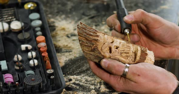 Close up male hands using power wood working tools graver, carving