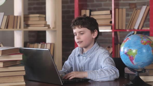 Modern school education. Portrait schoolboy a Desk among stacks of books. alt