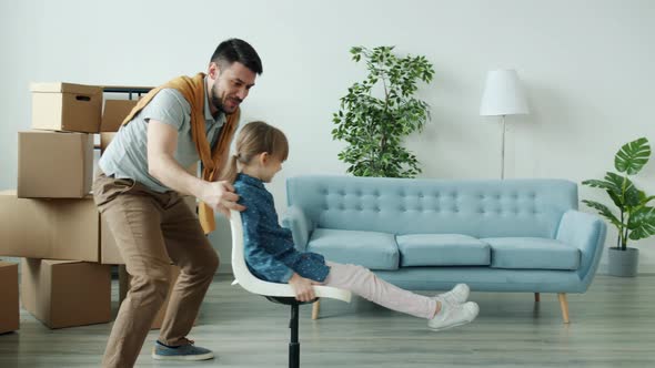 Caring Dad Having Fun with Daughter Pushing Chair with Kid Tickling Laughing in New House alt