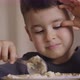 Boy Has Breakfast Eating Porridge Sitting at Home in the Kitchen on a High Chair - VideoHive Item for Sale