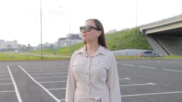 Beautiful Young Girl with Glasses Walks Through the City and Looks Around