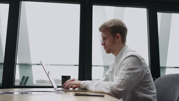 Businessman is Working with Notebook in Modern Office or Coworking Space Surfing Internet for Info alt