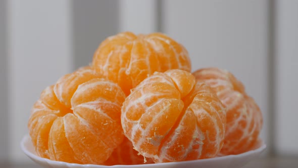 Peeled ripe tangerines in a bowl rotating on a table. Close up view.