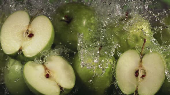 Slow Motion Shot of Green Apple Water Splashing Through Apple Slices alt