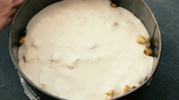 Woman's Hands Rotating the Batter with the Apple Slices in a Baking Sheet Covered with Parchment