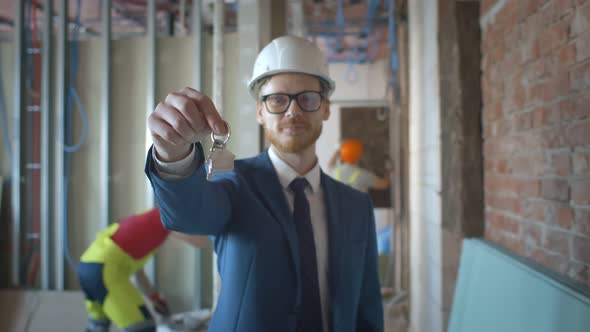 Happy Businessman Holding Keys on Construction Site alt