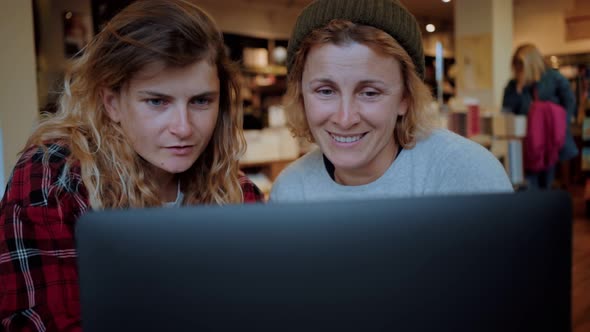 Two Women Work on Laptop in Cafe or Coworking alt