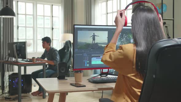 Back View Of Asian Female Video Editor Start Works With Footage And Sound On Her Personal Computer alt