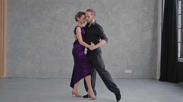 Man and Woman are Sensually Doing Tango Pose in Grey Studio