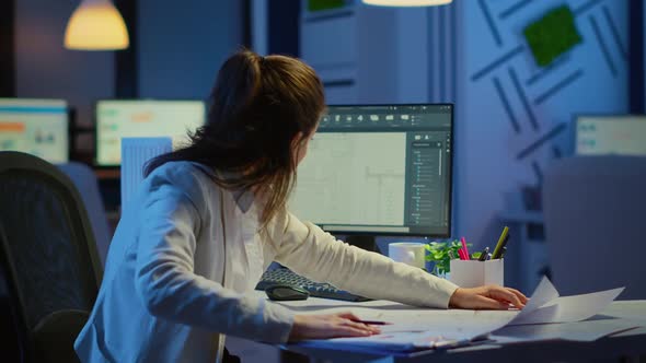 Focused Woman Architect Checking and Matching Blueprints Overtime alt